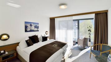 Habitación de hotel con una cama grande, un escritorio, una silla, una ventana con cortinas y vistas al exterior.