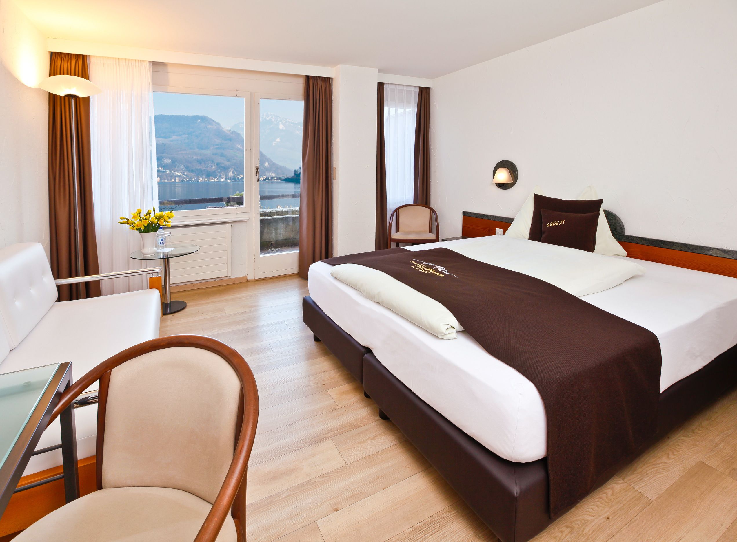A hotel room with a bed, a desk, a chair, and a view of mountains through the window.