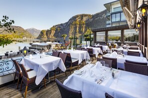 An outdoor dining area with tables set for guests, overlooking a lake and mountains. - Seehotel Pilatus (Hergiswil)