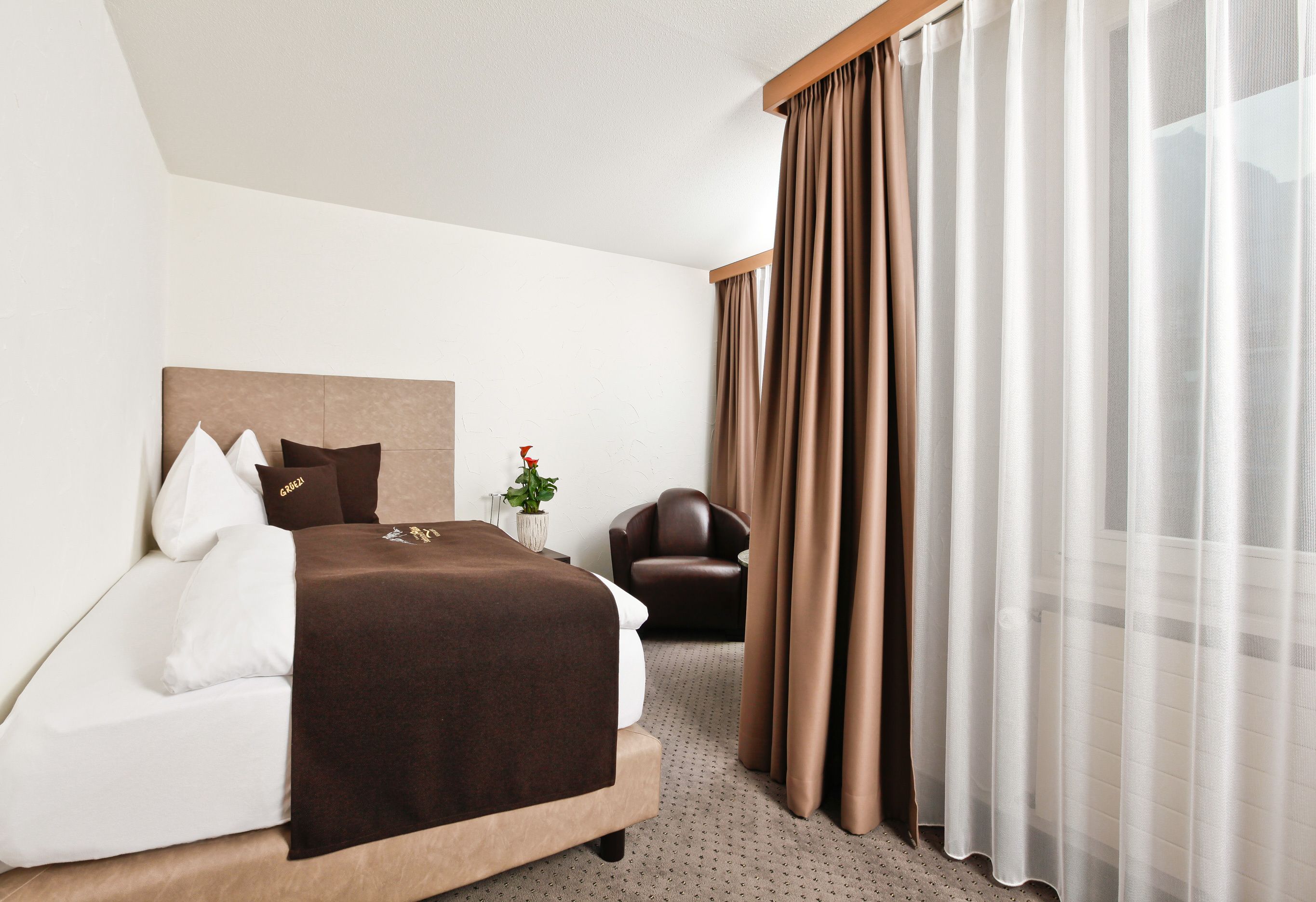 Une chambre d’hôtel avec un grand lit, une chaise et une fenêtre avec des rideaux.