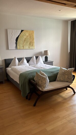A neatly made bed with white bedding and a green throw, a bedside table with a lamp, and a large abstract painting on the wall. - Hotel Restaurant Bellevue au Lac (Hilterfingen)