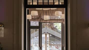 Vista del interior de un comedor con una mesa, sillas, una lámpara de araña y vistas a través de una ventana.
