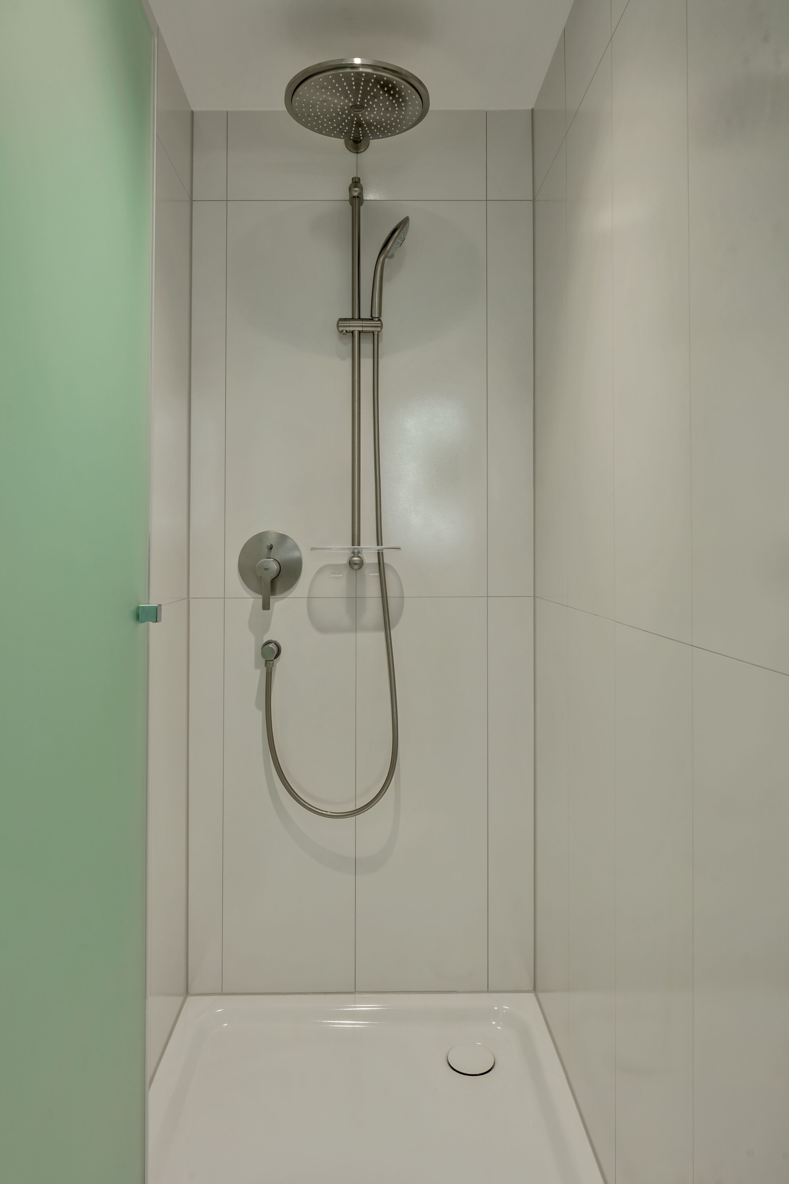Une douche équipée d’un pommeau de douche à main et d’un panneau de commande fixé au mur.