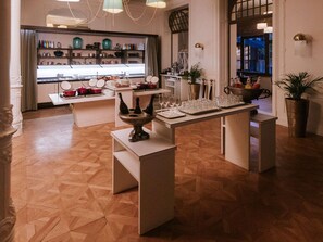 Un intérieur moderne avec un bar central, un présentoir d’ustensiles de cuisine et un espace repas aménagé.