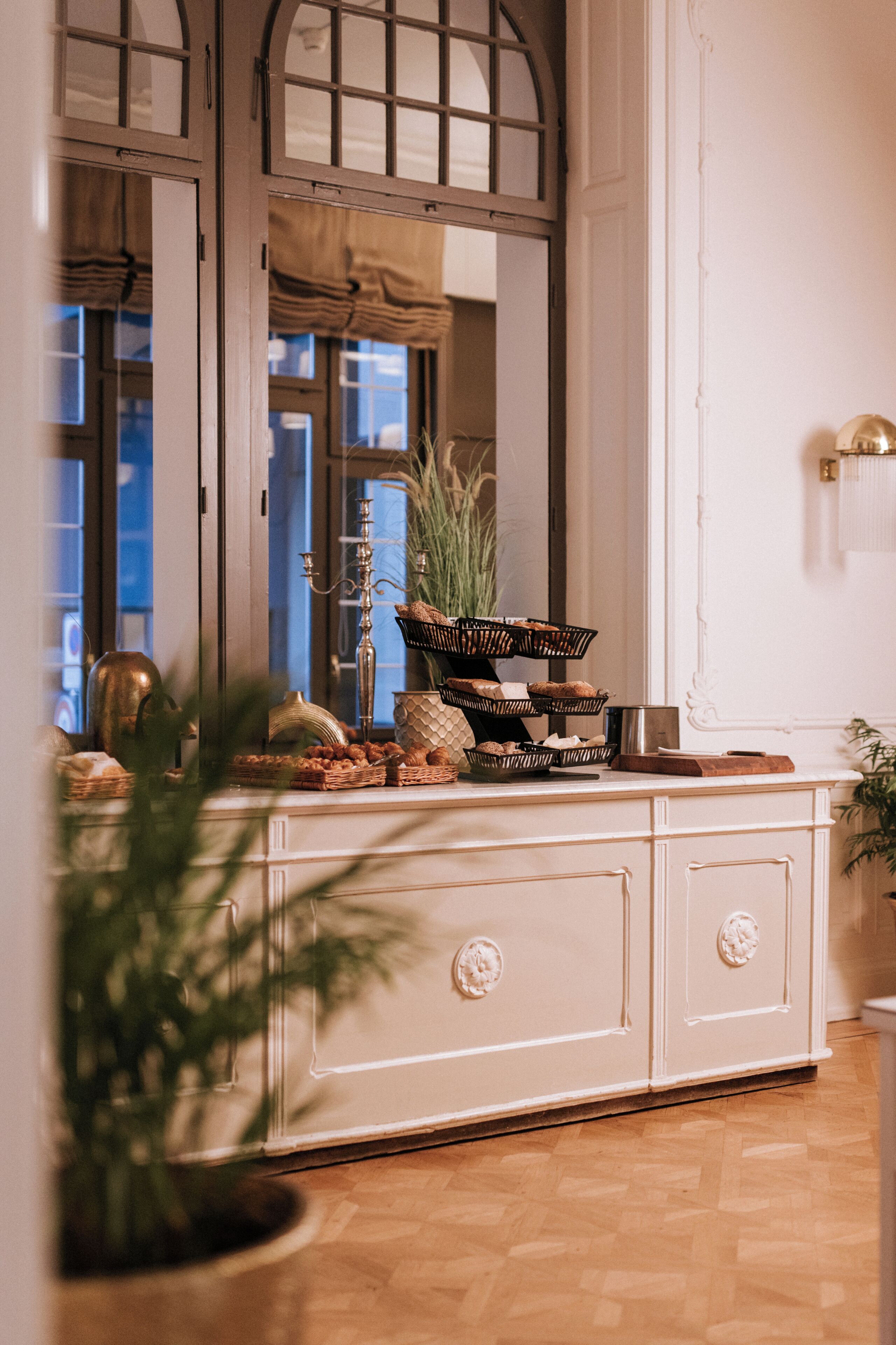 A kitchen with a wooden countertop, a potted plant, and a window with curtains.