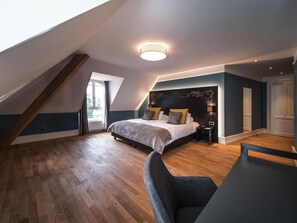 Une chambre avec un plafond en pente, un lit avec des oreillers, une table de chevet et une chaise.