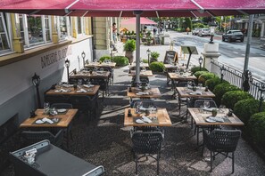 Un espace extérieur aménagé pour les repas, avec des tables et des chaises, un parasol rouge et une enseigne indiquant « BRASSERIE ST. GEORGES ».
