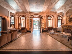 Un vaste hall d’entrée agrémenté de fenêtres en arc de cercle, d’un lustre et d’une cheminée.