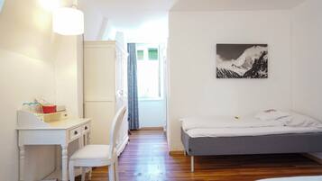 Un dormitorio con una cama, un escritorio y una silla. Hay una ventana con cortinas y un cuadro en la pared.