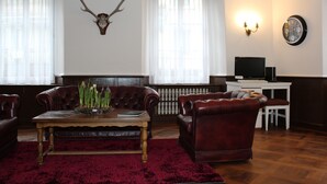 Una sala de estar con una mesa de centro de madera, sillones de cuero, un tapete rojo y una cabeza de venado montada en la pared.