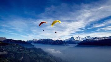 Un paysage montagneux, avec un ciel dégagé et deux parachutes visibles.