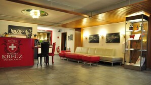 Un vestíbulo de hotel con mostrador de recepción, zona de estar y una exhibición de botellas de vino.