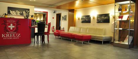 Un vestíbulo de hotel con mostrador de recepción, zona de estar y una exhibición de botellas de vino.