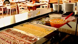 Un bufé con diferentes opciones de comida, incluyendo carnes, quesos y una ensalada de frutas.