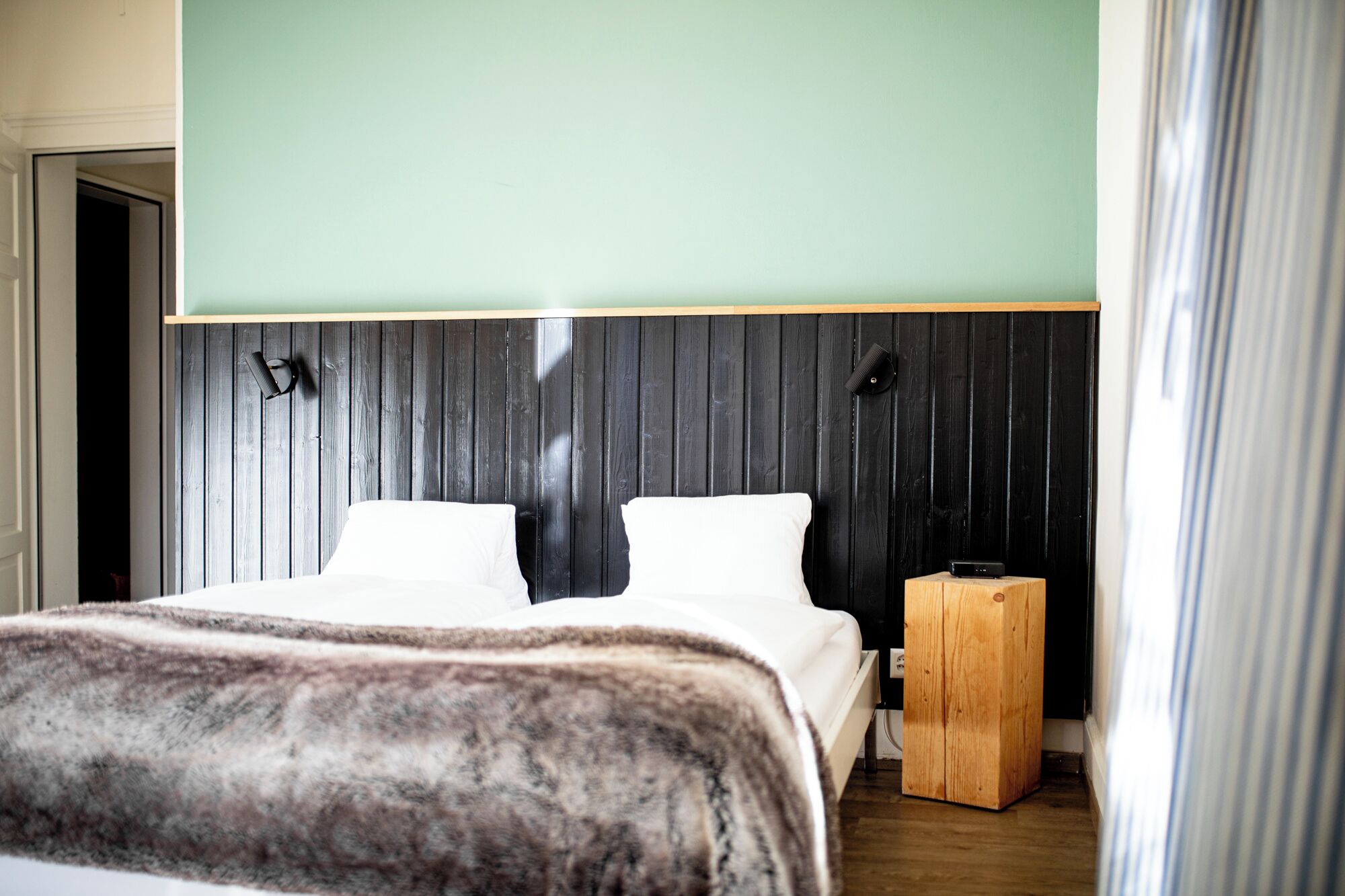 A bedroom with a bed, a wooden nightstand, and a headboard with vertical slats.