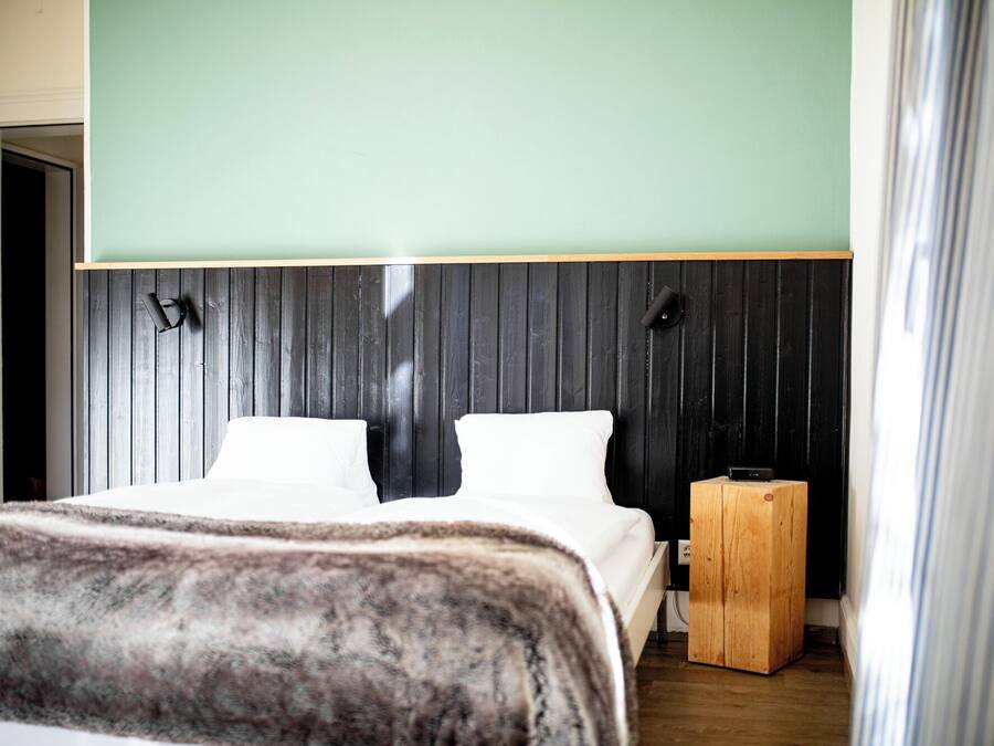A bedroom with a bed, a wooden nightstand, and a headboard with vertical slats.