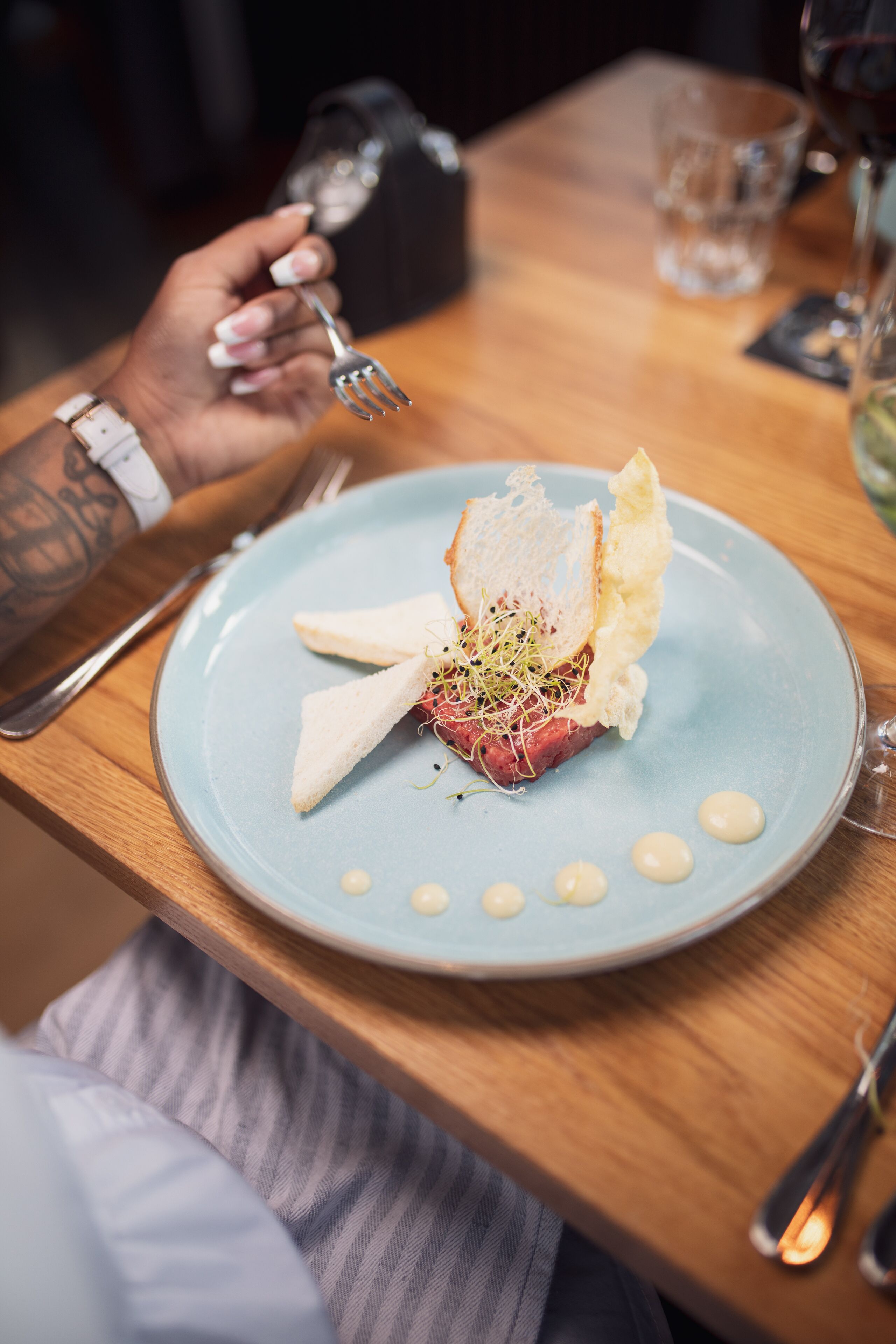 Un plato de comida sobre una mesa de madera, con una persona sosteniendo un tenedor.