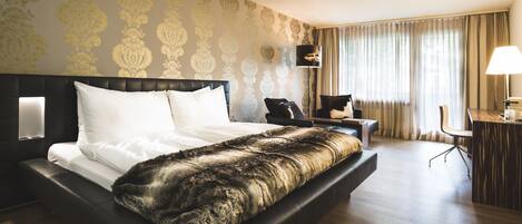 A hotel room with a large bed, a desk with a chair, and a lamp.