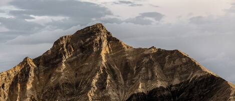 A mountain with rugged terrain and a cloudy sky.