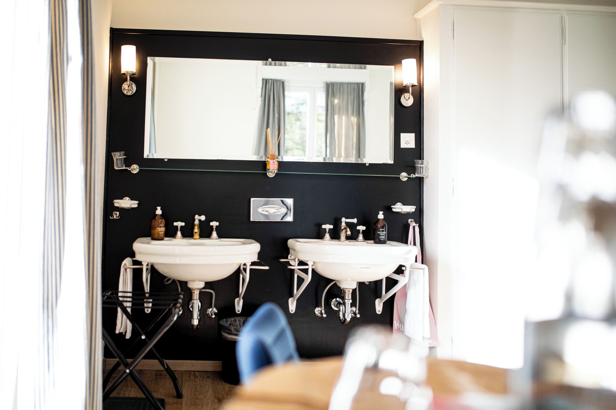 A bathroom with two sinks, a large mirror, and a black wall.