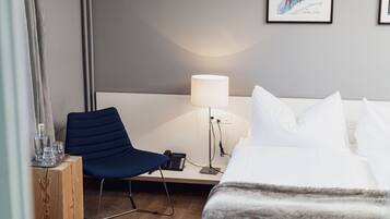 A hotel room with a bed, a desk with a chair, a lamp, and a framed picture on the wall.