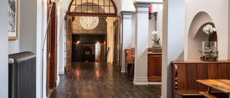 A hallway with wooden flooring, a fireplace, and a bench.