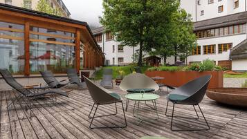 Une terrasse en bois avec un espace salon extérieur, comprenant des chaises longues et une table.