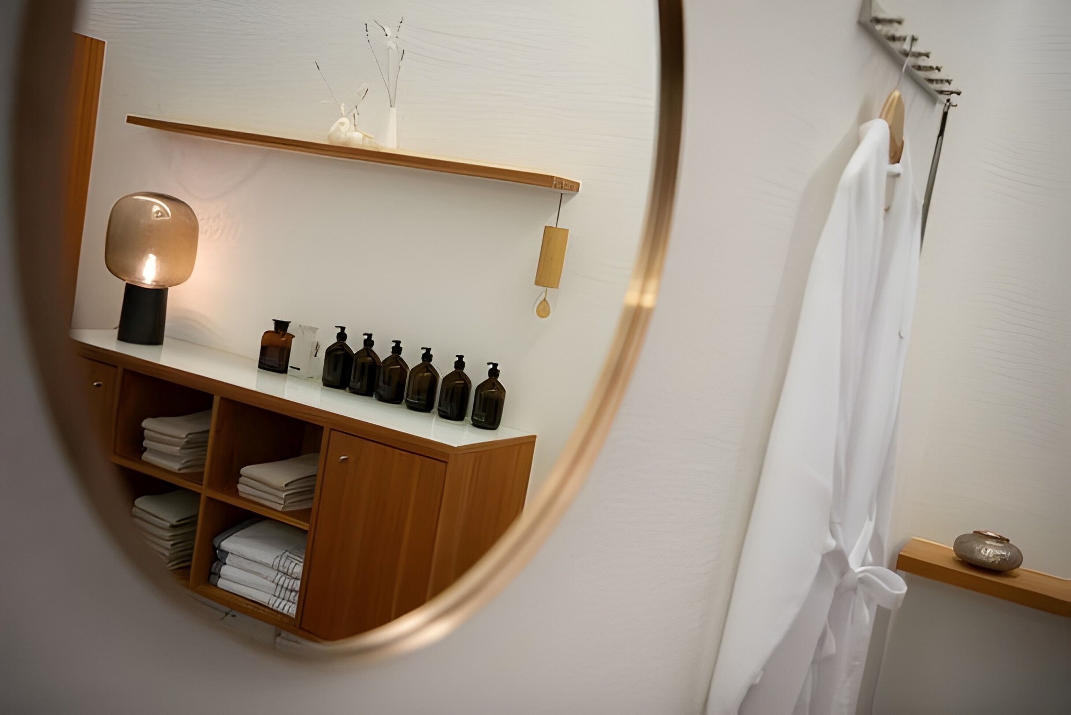 A bathroom with a wooden vanity, a mirror, and a shelf with toiletries.