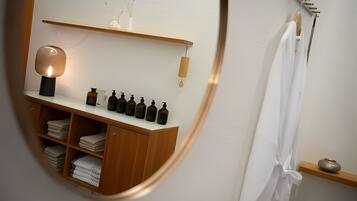 A bathroom with a wooden vanity, a mirror, and a shelf with toiletries.