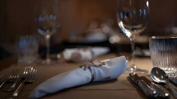 Une table dressée avec une serviette pliée, des couverts et un verre.