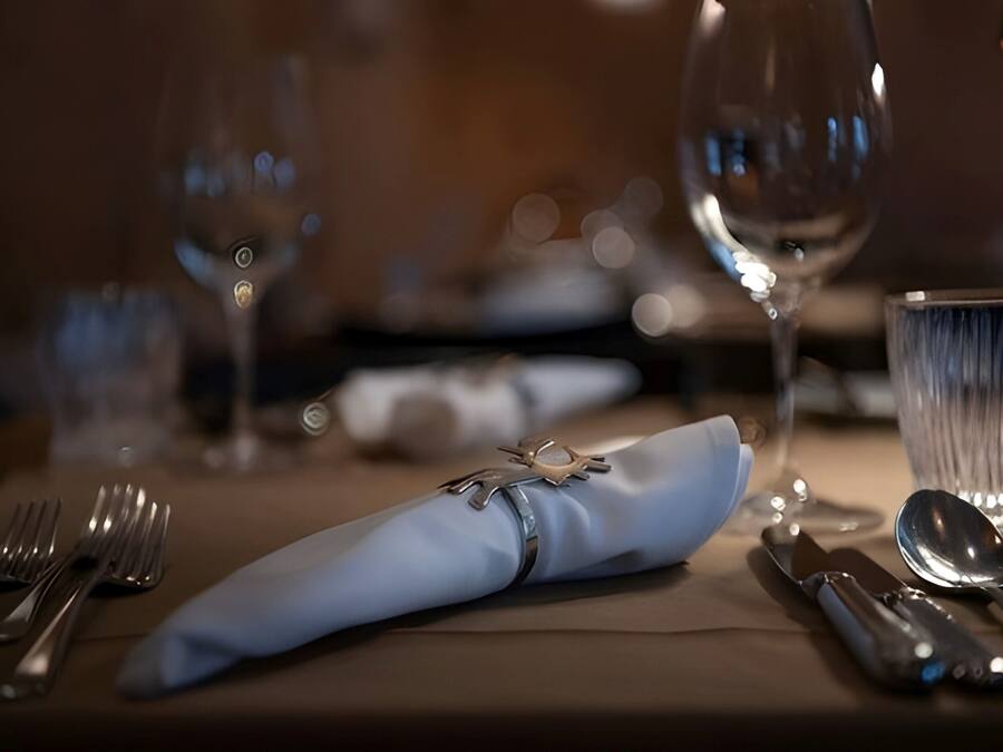 Une table dressée avec une serviette pliée, des couverts et un verre.