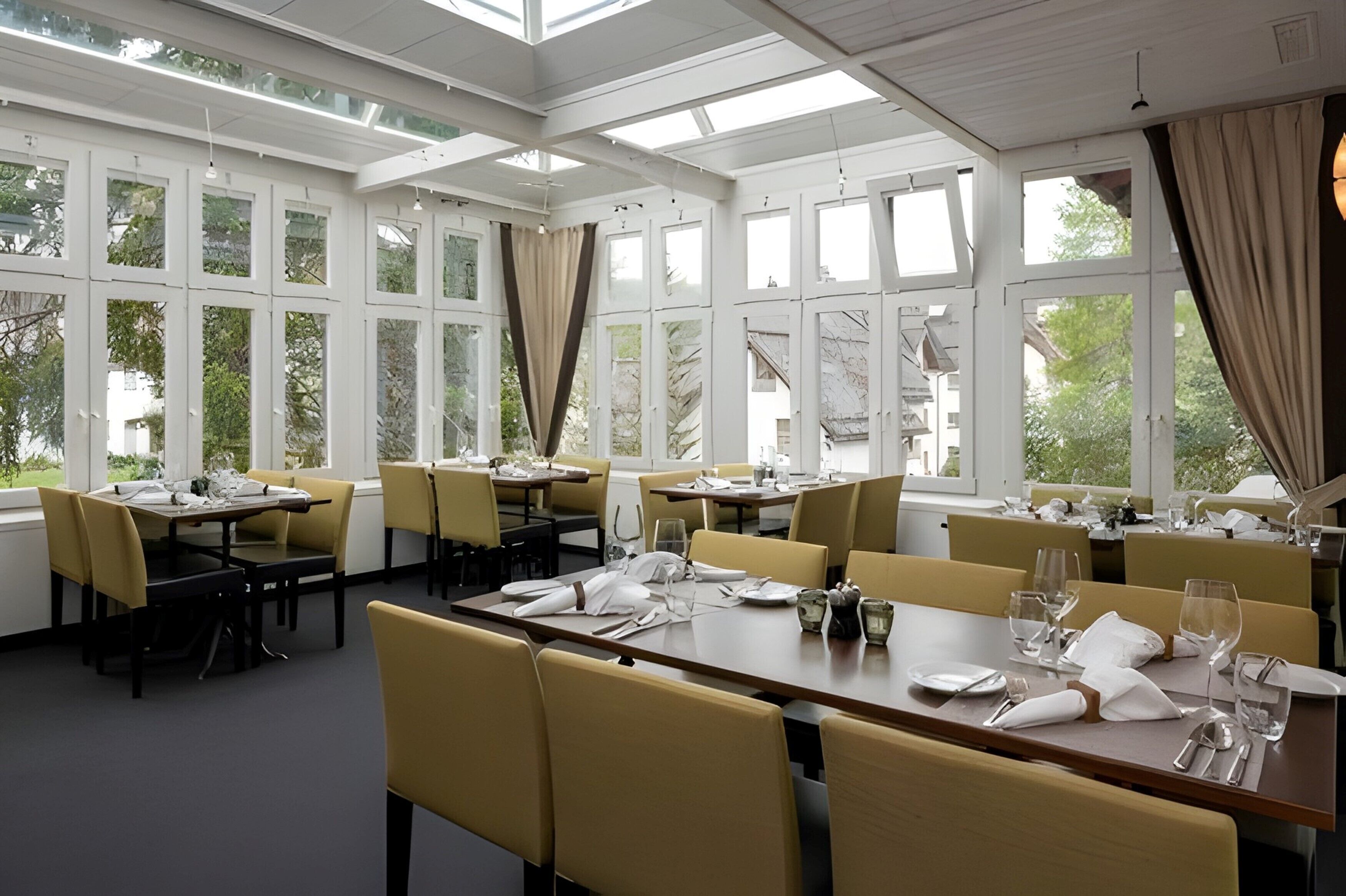 A restaurant with multiple tables, chairs, and large windows.