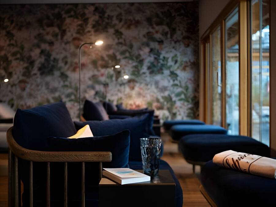 A modern living room with dark blue sofas, a wooden coffee table, and a floral wallpaper.
