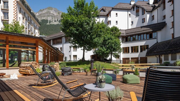 A wooden deck with outdoor seating, a table, and potted plants.