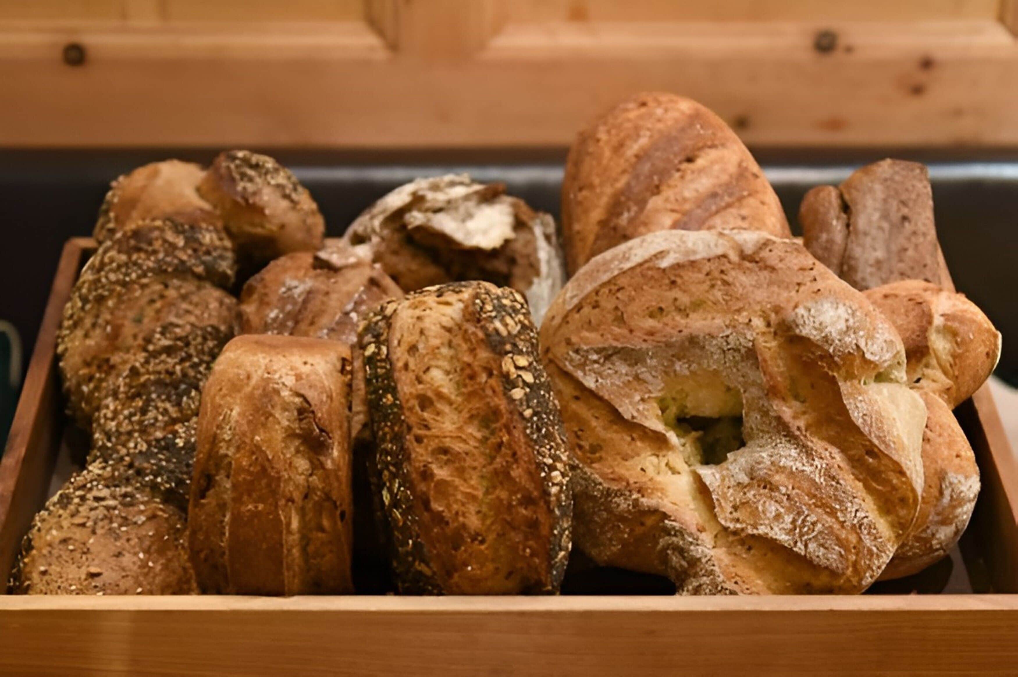 Eine Holzkiste mit verschiedenen Brotsorten, darunter Brot mit Saaten und knuspriges Brot.