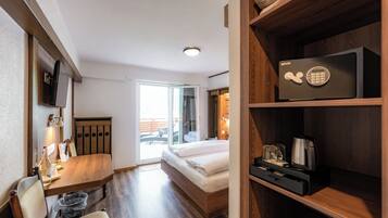 A hotel room with a bed, a desk, a television, a microwave, and a view of the outside.