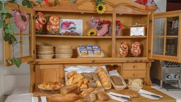 Mostrador de panadería con diferentes panes y pasteles, una rebanadora y elementos decorativos.