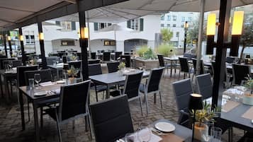 Un espacio de comedor al aire libre con mesas, sillas y sombrillas.
