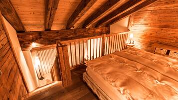 A wooden cabin bedroom with a bed, a nightstand, and a window.
