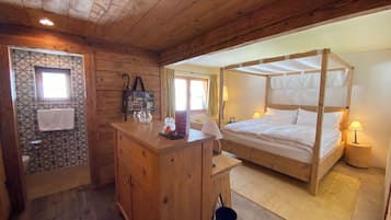 Ein schlafzimmer im Holzblockhausstil mit einem Himmelbett, einer Holzkommode und einem kleinen Schreibtisch.