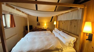 Una habitación con cama con dosel, paredes de madera, un escritorio con silla y una lámpara.