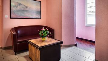 Eine Lobby mit einem Holztisch, einem roten Sofa und einem Gemälde an der Wand.