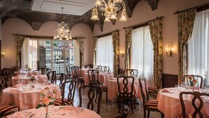 Un restaurant avec des tables rondes, des chaises et un lustre.