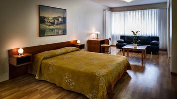 Ein Hotelzimmer mit einem großen Bett, einem Schreibtisch, einem Sessel, einer Couch und einem Bild an der Wand.