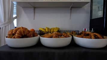 Tre vita skålar fyllda med croissanter och bananer står på ett bord.