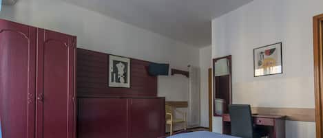 A room with a bed, a desk, a chair, a wardrobe, and a radiator.
