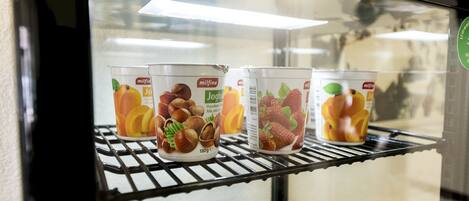 Vitrina refrigerada con tres recipientes de yogur, cada uno con un sabor a fruta diferente.