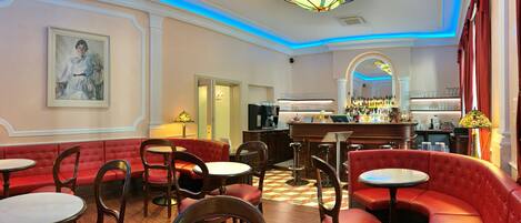 A restaurant with red upholstered booths, round tables, and a bar area with a counter and shelves of bottles.