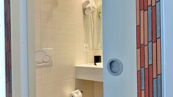 Un baño con inodoro, perchero para toallas, secador de pelo y dispensador de papel higiénico.
