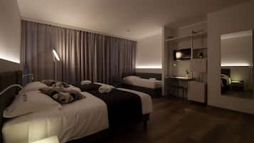 Two single beds with crisp linens and plush pillows, a desk with chair, and a mirror above, set against a backdrop of a large window with curtains.